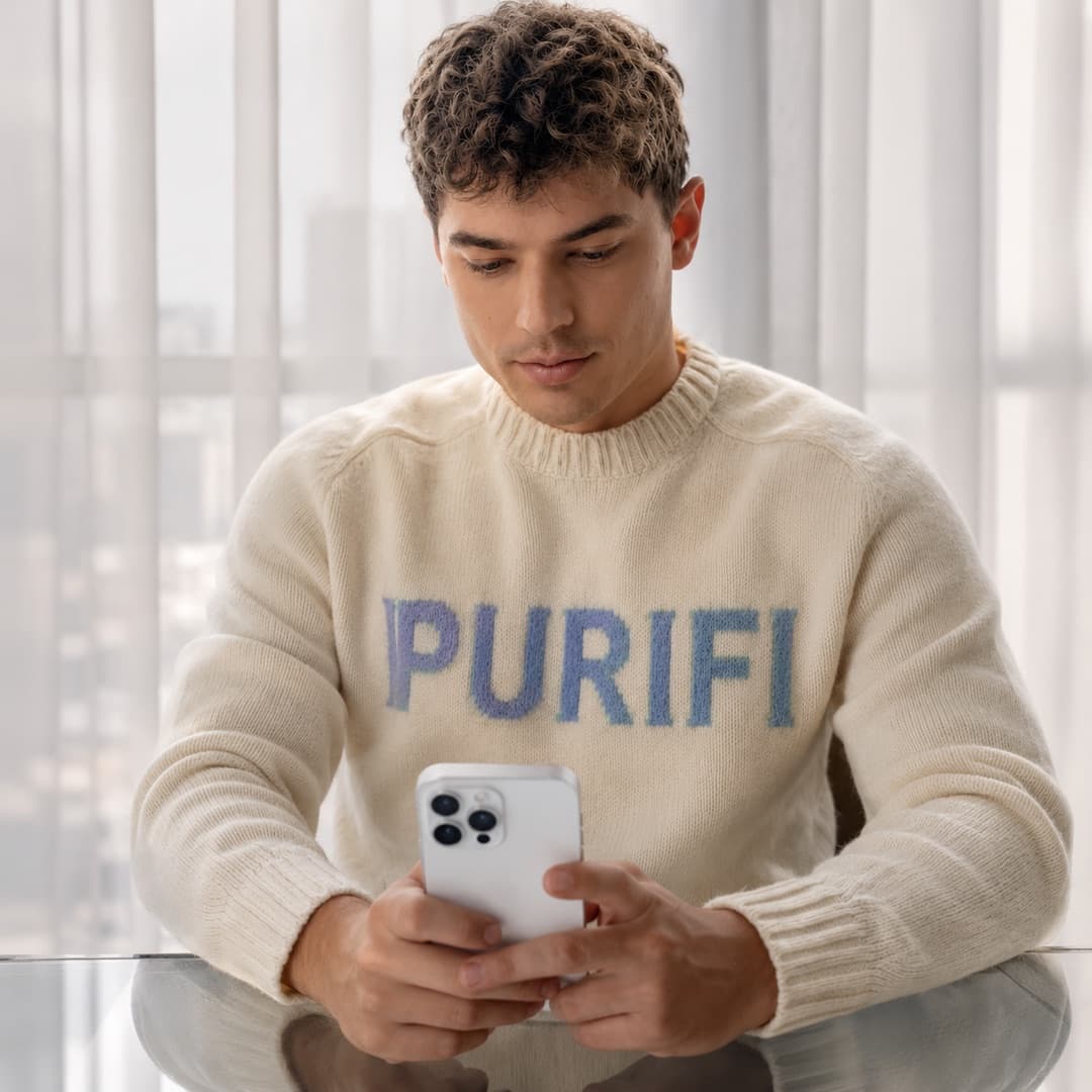 A man at a glass table pairing PuriFi with the app on his phone.